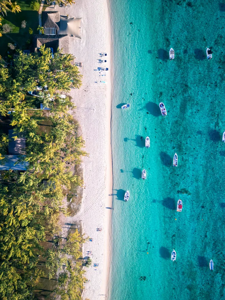 Aerial view of a white sand beach with boats resting on turquoise water