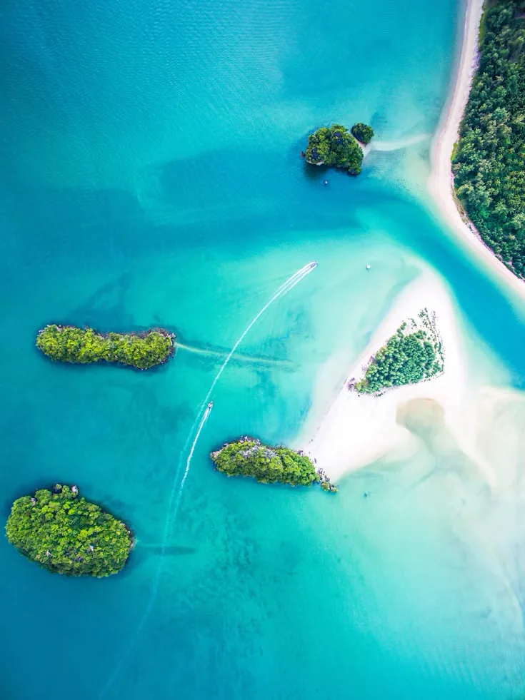 Small green islands and sandbars in clear turquoise water