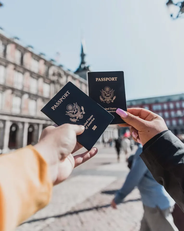 Two travellers holding up their passports in a city square
